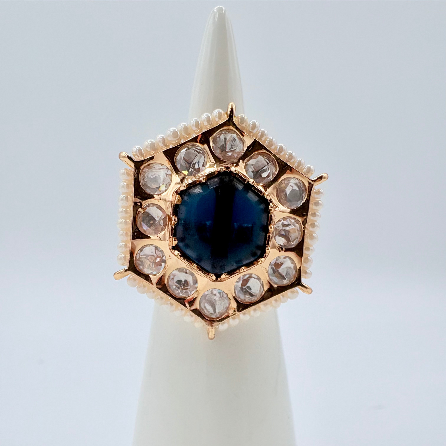 Gold ring with a navy blue gemstone surround by small crystal gems available at Nishaani.ca – Indian jewelry in Canada