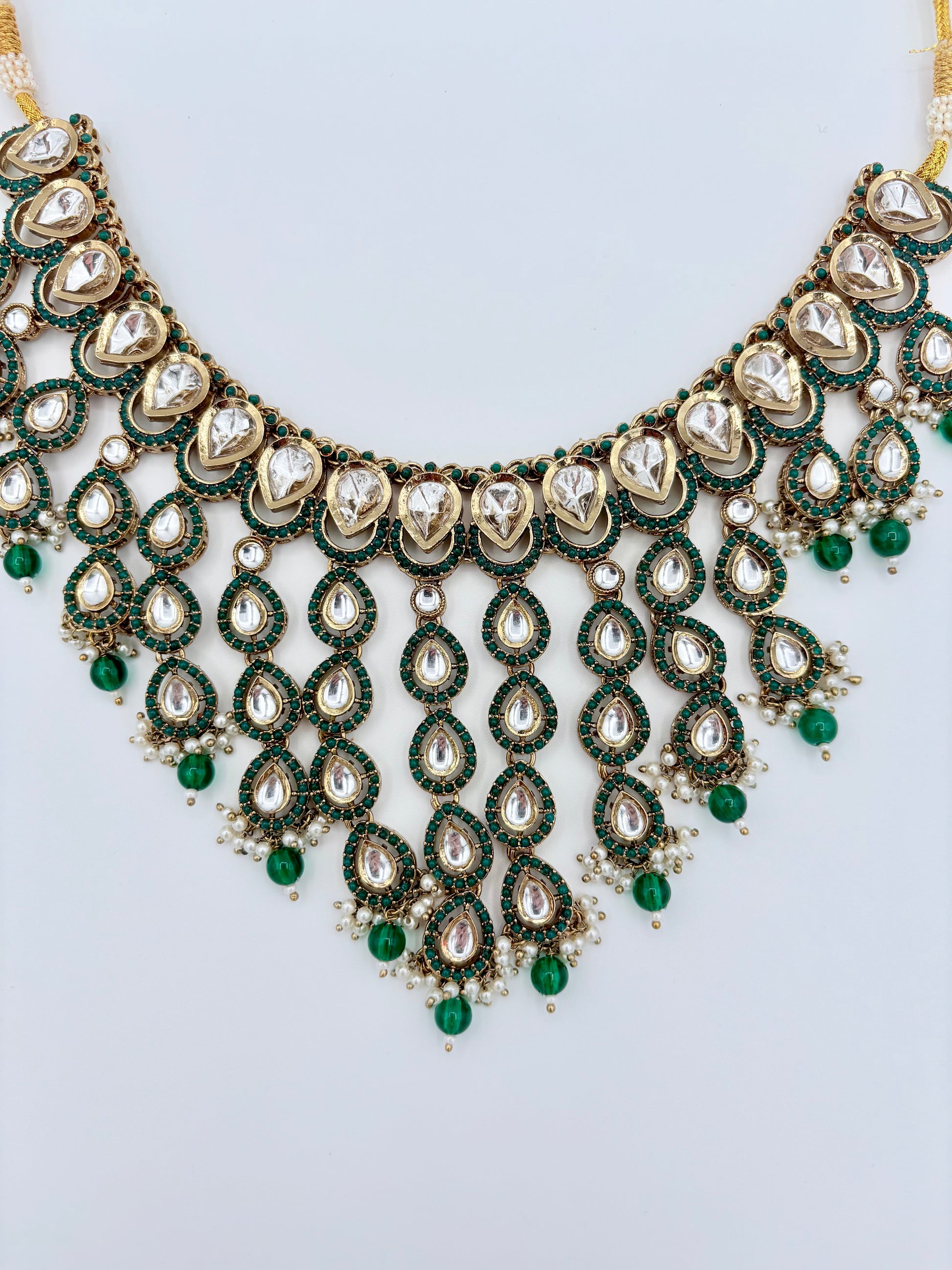 Ornate necklace with green and gold accents on a light gray background available at Nishaani.ca – Indian jewelry in Canada