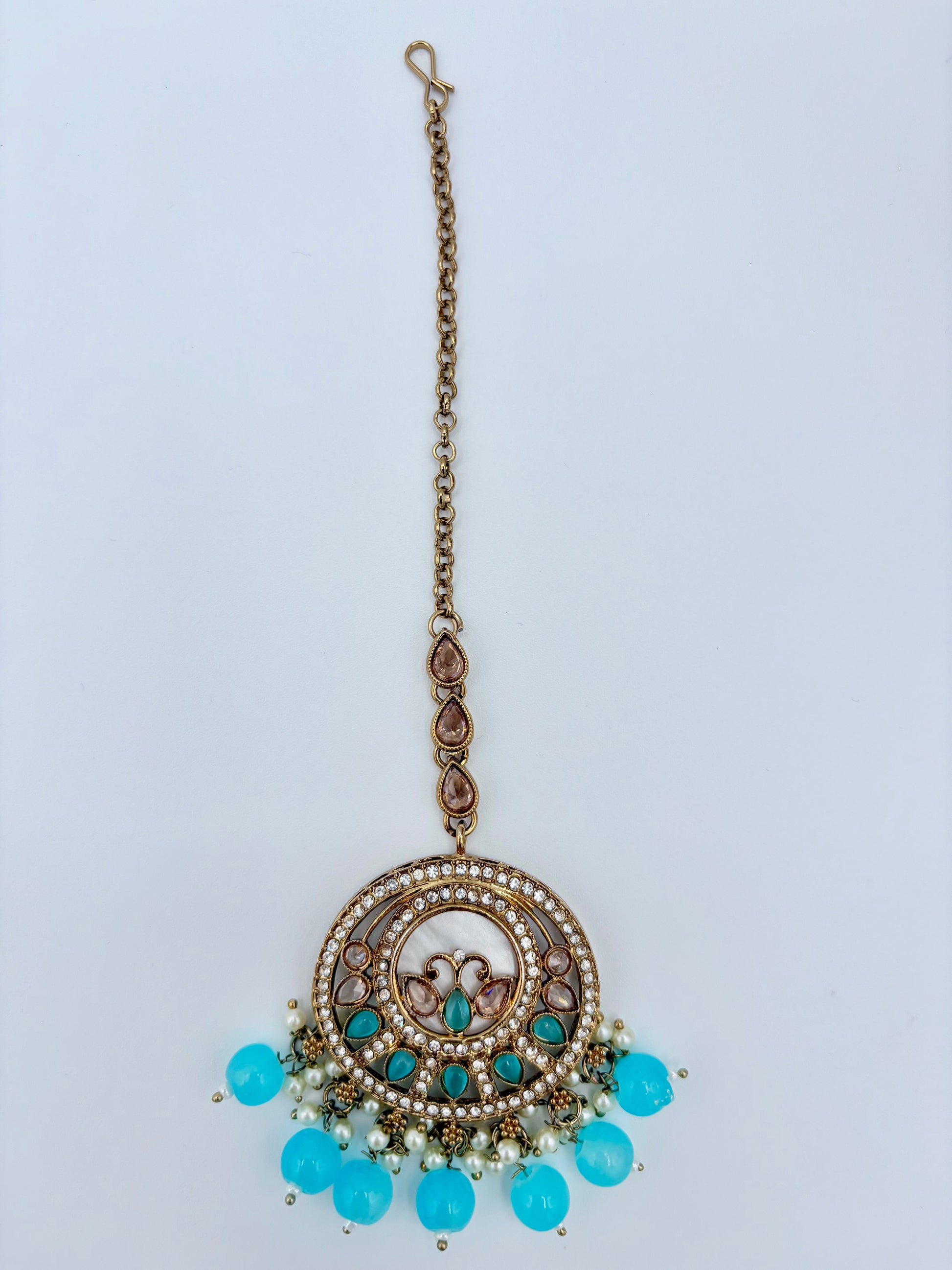 Tikka with turquoise beads and gold chain on a light blue background