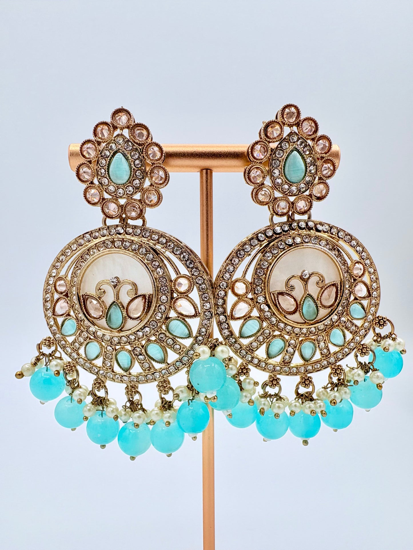 Ornate earrings with turquoise beads on a stand available at Nishaani.ca – Indian jewelry in Canada