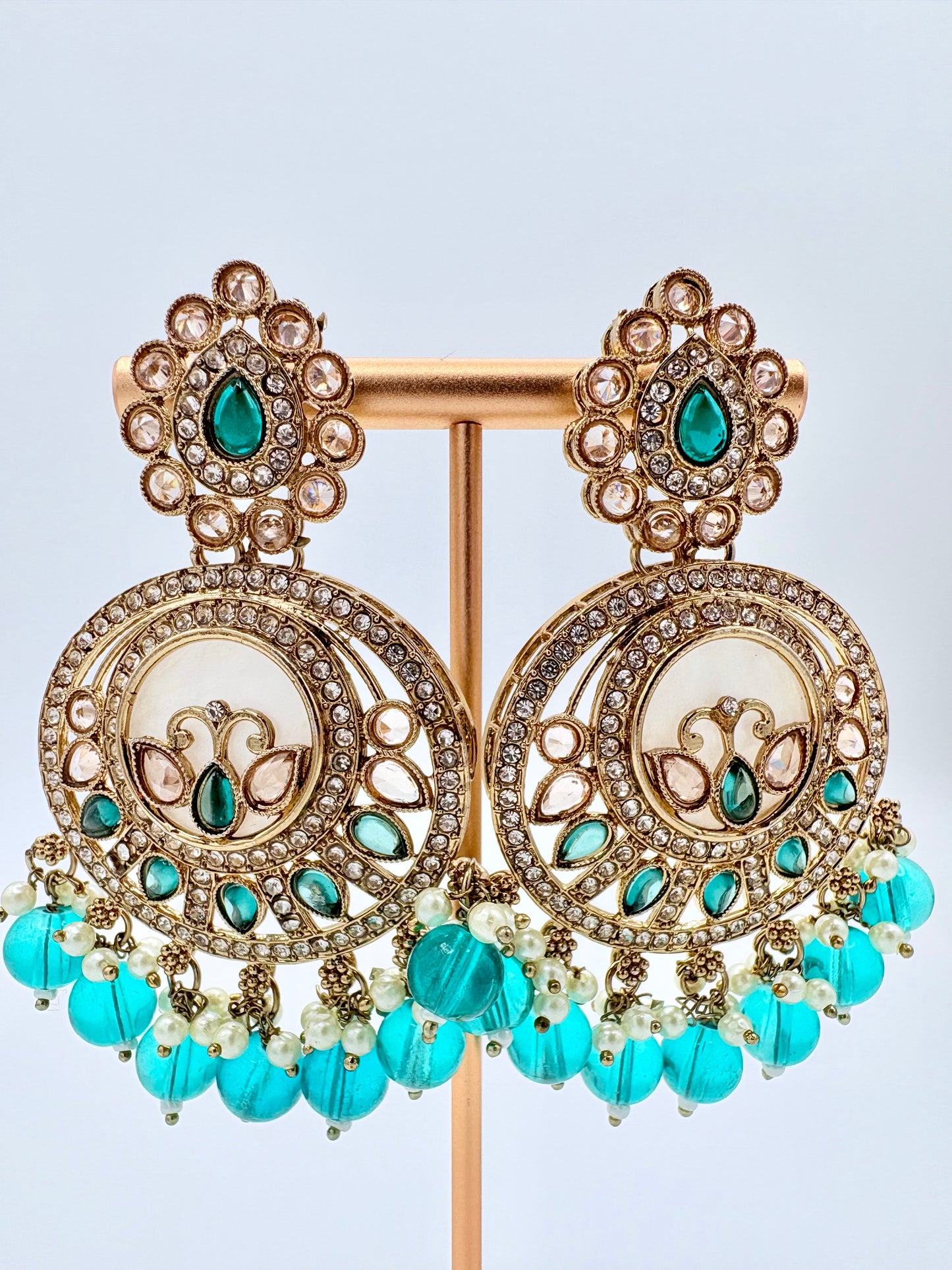 Ornate earrings with turquoise beads and gemstones on a stand available at Nishaani.ca – Indian jewelry in Canada