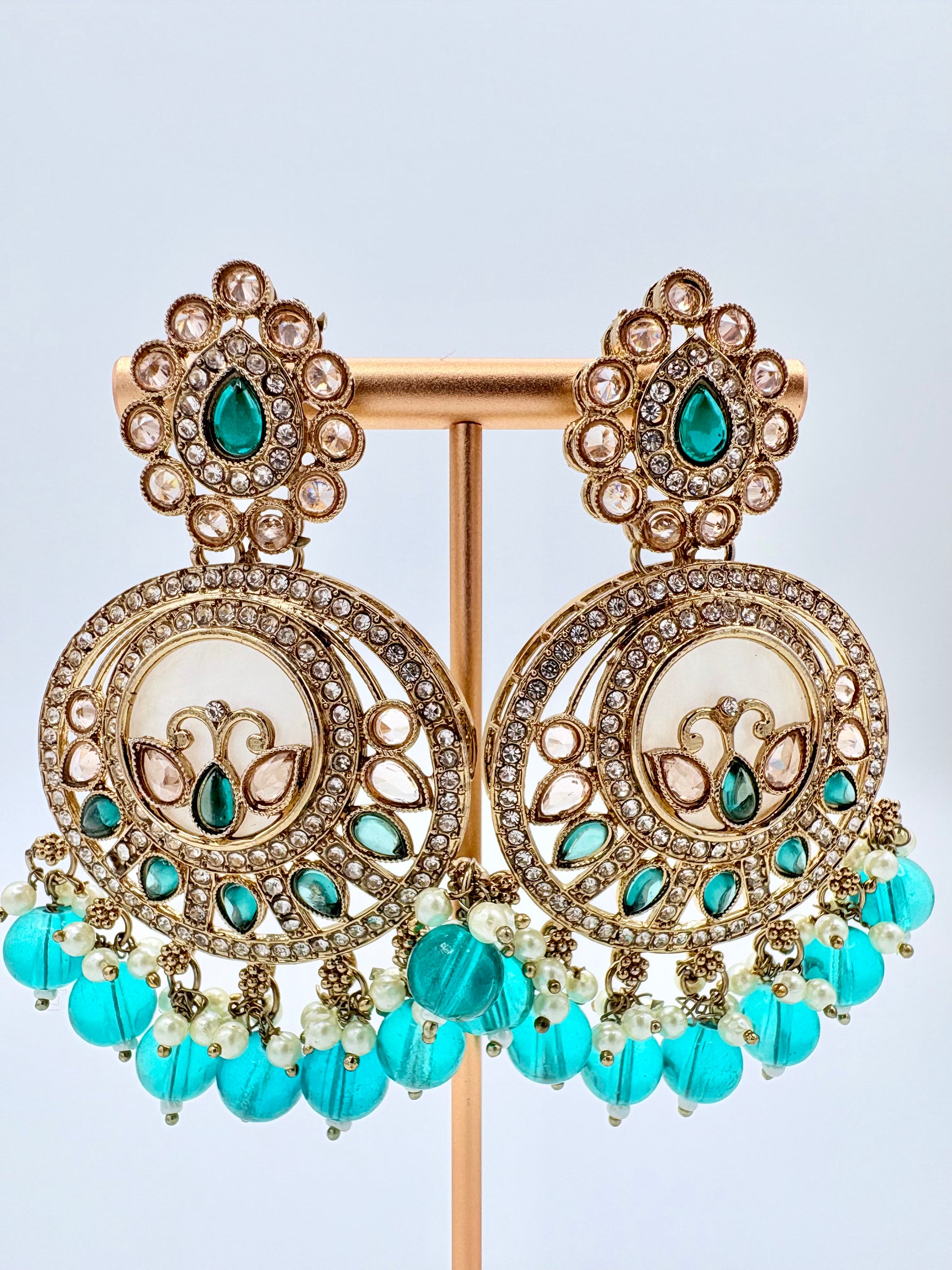 Ornate earrings with turquoise beads and gemstones on a stand available at Nishaani.ca – Indian jewelry in Canada