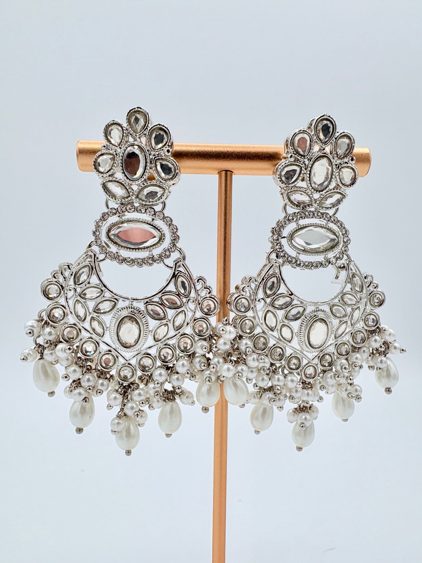 Ornate silver earrings with clear stones on a stand available at Nishaani.ca – Indian jewelry in Canada