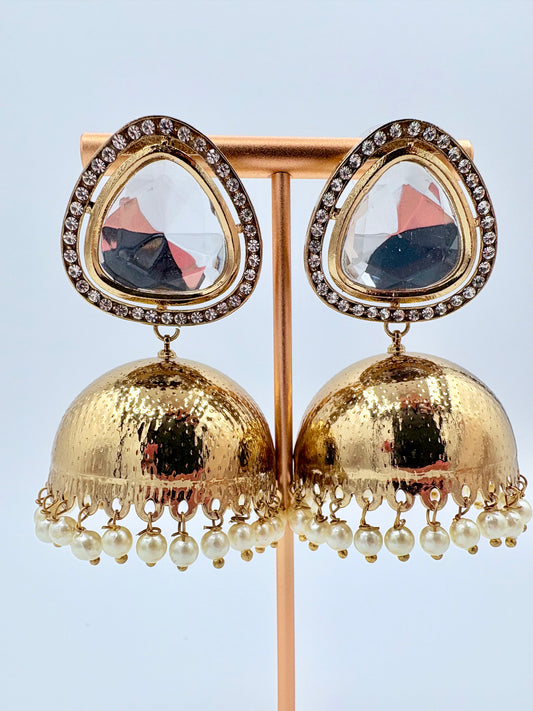 Gold earrings with teardrop-shaped tops and pearl drop details on a stand available at Nishaani.ca – Indian jewelry in Canada
