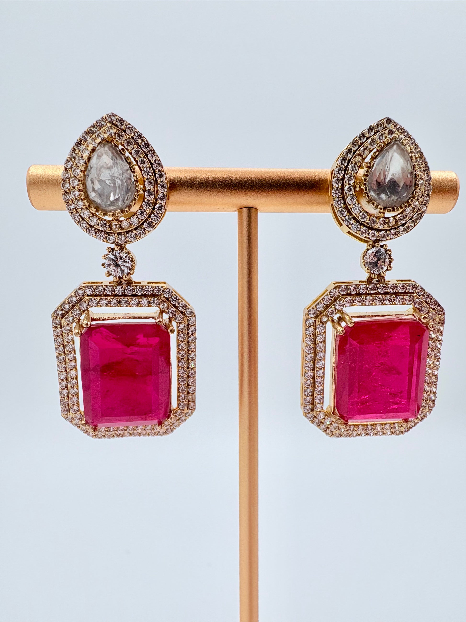 Pair of earrings with red gemstones on a gold available at Nishaani.ca – Indian jewelry in Canada