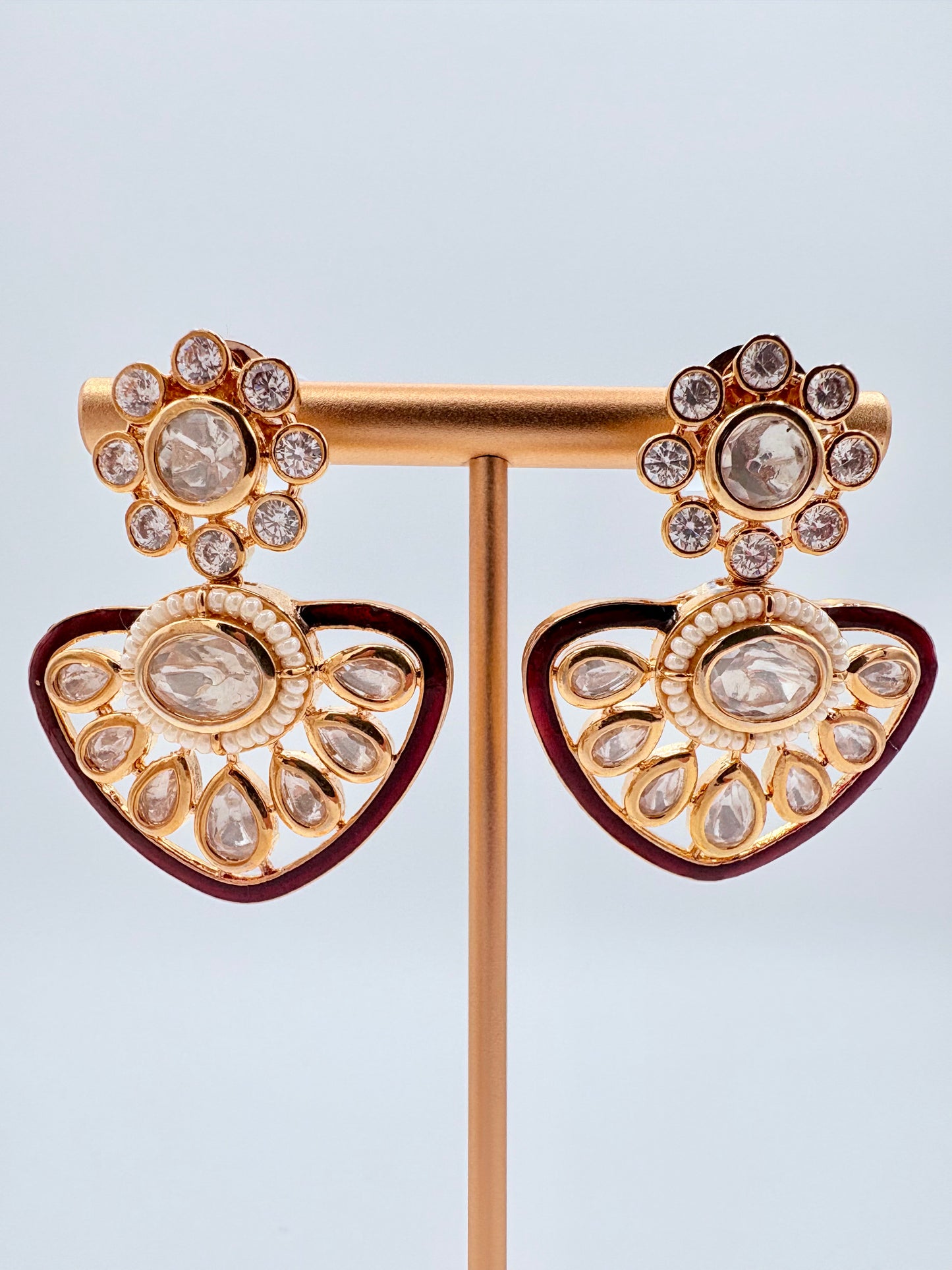 Ornate gold and red earrings on a stand available at Nishaani.ca – Indian jewelry in Canada